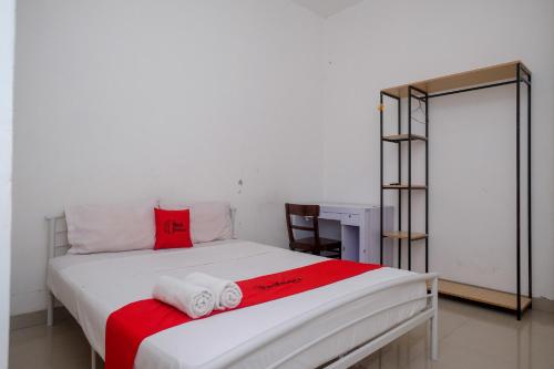 1 dormitorio con 1 cama con toallas en RedDoorz at Golden White House Pettarani en Makassar