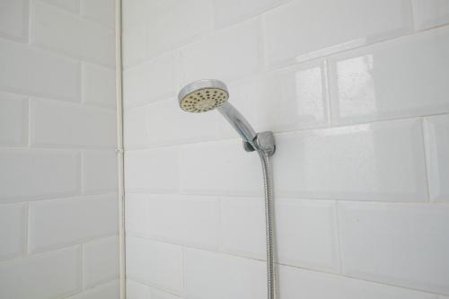 a shower with a shower head in a bathroom at RedDoorz at Golden White House Pettarani in Makassar