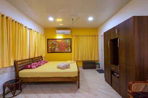 a bedroom with a bed and a yellow wall at Vasudevam Premium Suites in Trivandrum