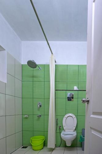 a green bathroom with a toilet and a shower at Vasudevam Premium Suites in Trivandrum