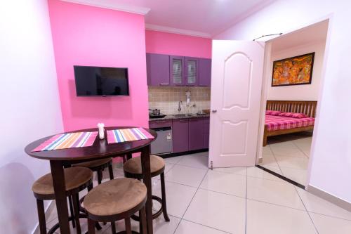 a kitchen with pink walls and a table and stools at Vasudevam Premium Suites in Trivandrum