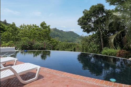 een zwembad met een witte stoel ernaast bij Villa La Fortuna Altos del Maria in Filipina