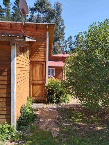 a wooden building with a door next to a tree at Cabañas Ocean Forest in El Tabo