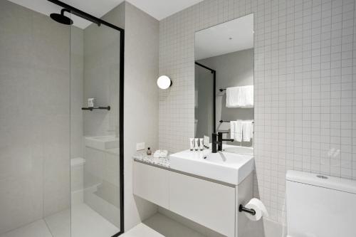 a white bathroom with a sink and a shower at Quest Collingwood in Melbourne