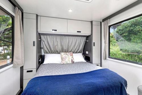 a bedroom in an rv with a bed and two windows at Reflections Seal Rocks - Holiday Park in Smiths Lake
