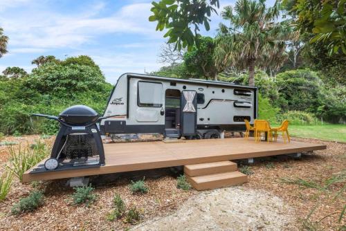 an rv with a wooden deck and a grill at Reflections Seal Rocks - Holiday Park in Smiths Lake