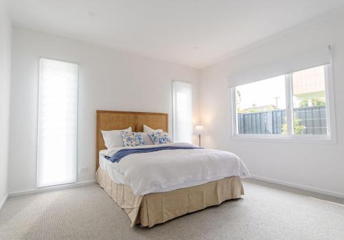 Un dormitorio blanco con una cama grande y una ventana en Palm Tree Retreat, en Mollymook