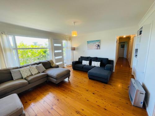 a living room with a couch and a tv at Relaxed Coastal Retreat in Mollymook
