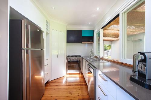 a kitchen with white cabinets and a stainless steel refrigerator at Relaxed Coastal Retreat in Mollymook