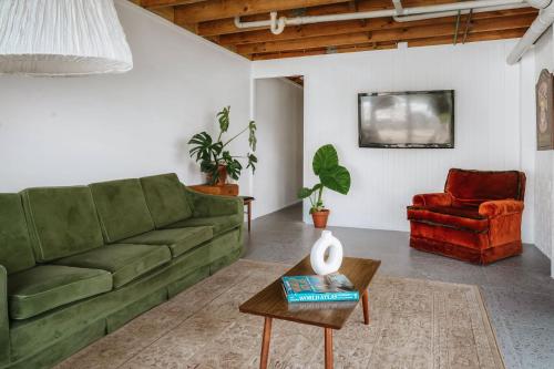 a living room with a green couch and a red chair at Suey's Coastal Farm House in Milton
