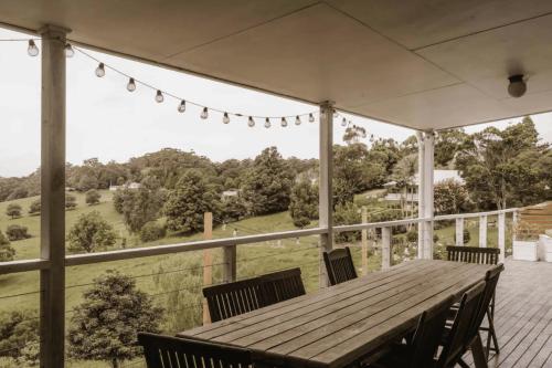 a wooden table and chairs on a porch with a view at Suey's Coastal Farm House in Milton