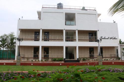 a white building with a garden in front of it at Sea Land Kihim in Alibaug