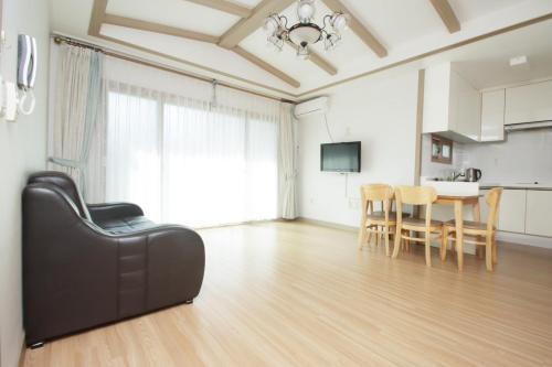 a living room with a table and a black leather couch at Jeju Soranghozen Pension in Seogwipo