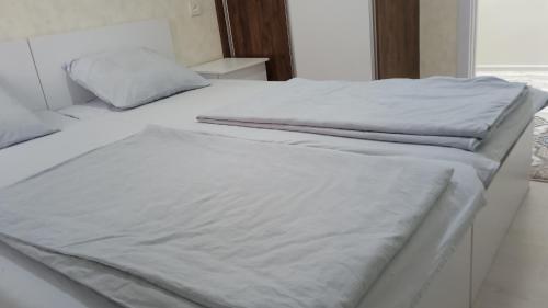 two unmade beds in a bedroom with white sheets at Begzod's room in Samarkand