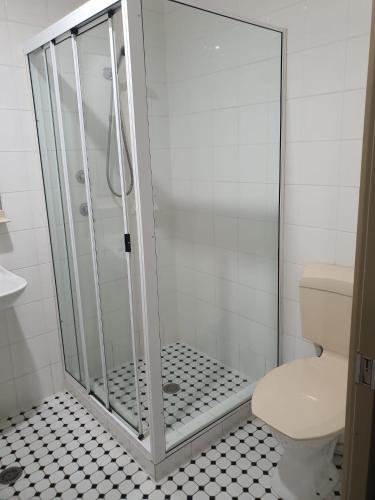 a shower stall in a bathroom with a toilet at Kambah Inn in Kambah