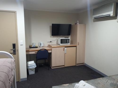 a room with a desk with a microwave and a tv at Kambah Inn in Kambah