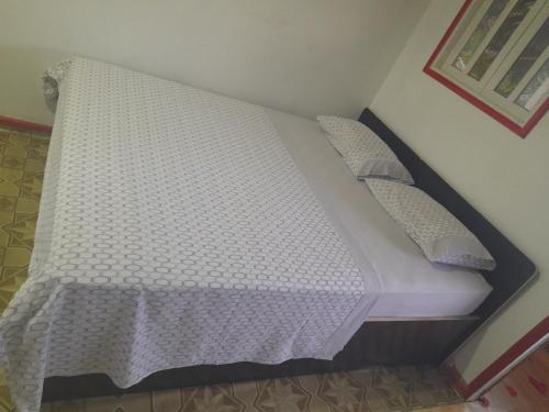 een bed met witte lakens en kussens in een kamer bij Beco Benfica in Trindade