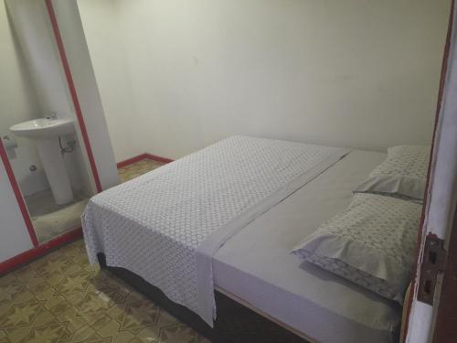 een wit bed in een kamer met een spiegel bij Beco Benfica in Trindade