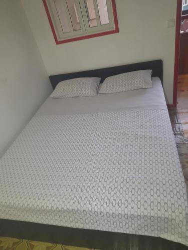 een bed met witte lakens en kussens in een slaapkamer bij Beco Benfica in Trindade