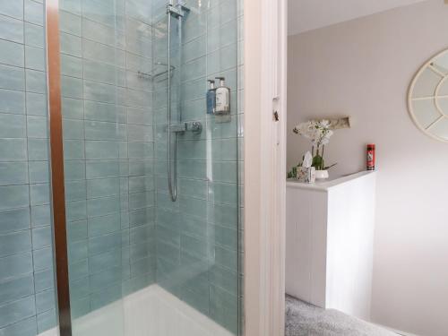 a bathroom with a shower with blue tiles at Millgate Cottage in Conwy