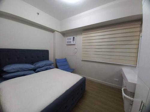 Un dormitorio con una cama con almohadas azules y una ventana en Lovely 1 bedroom at Vista Shaw Residences, en Manila