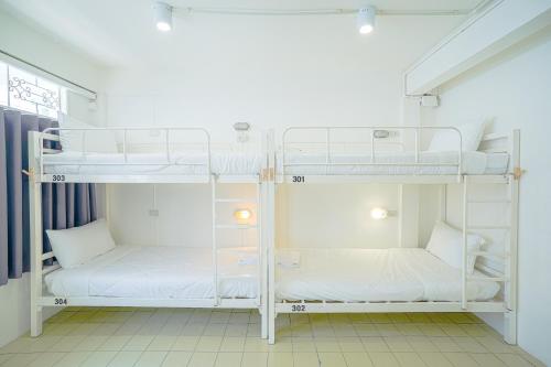 two bunk beds in a room with white walls at PICCOLO SUKHUMVIT HOSTEL in Bangkok