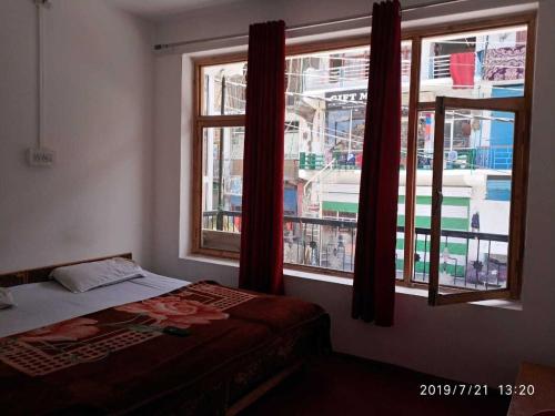 a bedroom with a bed and two windows at OYO Holidayinn in Kargil