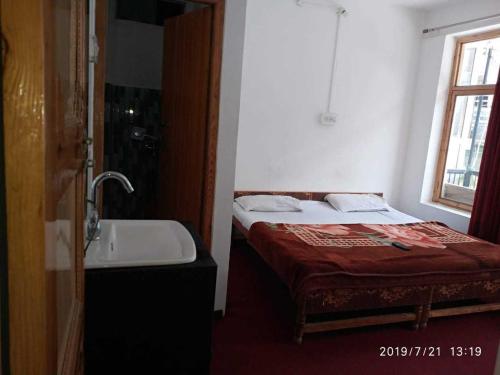 a small bedroom with a bed and a sink at OYO Holidayinn in Kargil