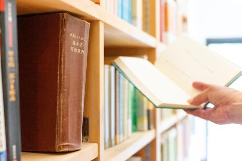 a person is holding a book in a library at Villa Noël Hakone Fuji Sauna&Open Air Bath in Hakone