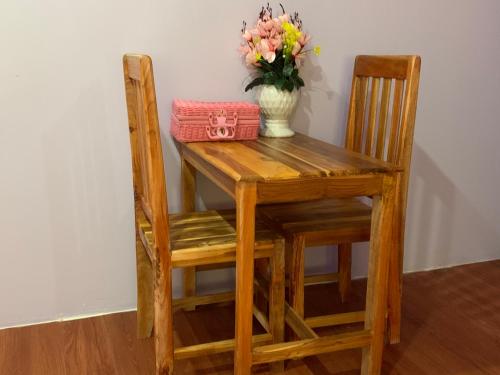 a wooden table with two chairs and a vase of flowers at Heaven Guesthouse in Pakse
