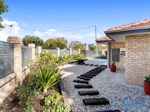 a garden with a stone walkway next to a house at Hot Spot on Hackett in Mandurah in Mandurah