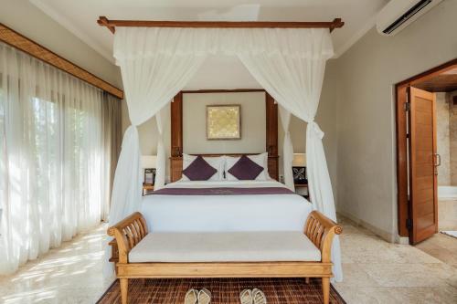 a bedroom with a white bed with a canopy at Desa Swan Villas & SPA, Keramas in Keramas