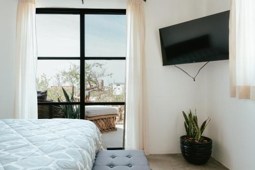 a bedroom with a bed and a flat screen tv at Casa De Surfos Cerritos’s Beach in San Carlos