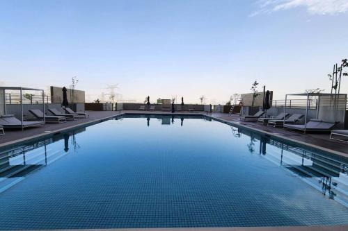 een groot zwembad met stoelen en blauw water bij STAY BY LATINEM Luxury 1BR Holiday Home CVR B3102 near Burj Khalifa in Dubai