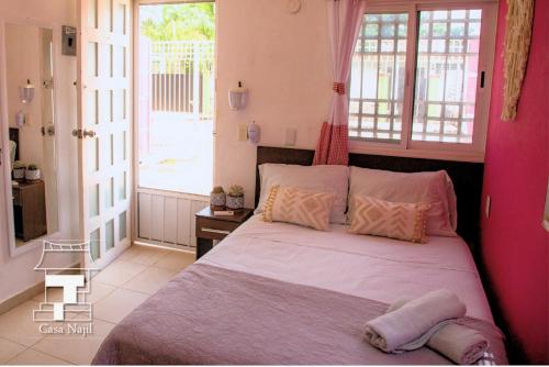 a bedroom with a large bed with pink walls at Najil House St1 in Bacalar