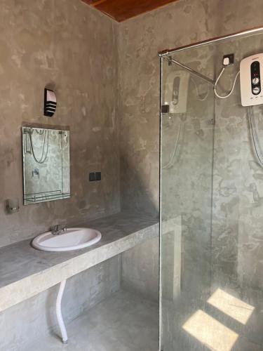 a bathroom with a sink and a glass shower at Sunrise Cabanas in Arugam Bay
