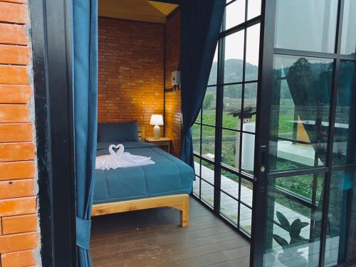 um quarto com uma cama e uma grande janela em The Maewin Coffee & Cottage Economy Double Room em Ban Huai Rin