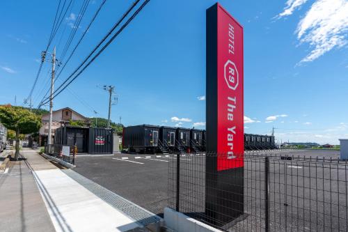 una señal roja en una valla al lado de un estacionamiento en HOTEL R9 The Yard Tomioka en Tomioka