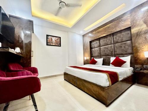 ein Schlafzimmer mit einem großen Bett und einem roten Stuhl in der Unterkunft Hotel Cosmo - Karol Bagh in Neu-Delhi