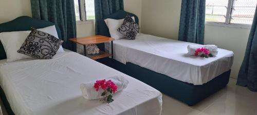 Dos camas en una habitación con flores. en ABM Court Apartments, en Nadi