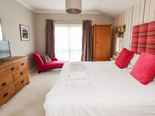 Un dormitorio con una gran cama blanca con almohadas rojas. en Cuddy's Holm, en Seahouses