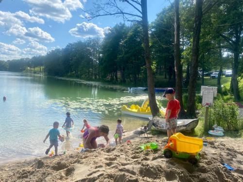 a group of children playing in the sand at a lake at Pole namiotowe - namiot do wynajęcia - Kurka Wodna !!! in Mikołajki