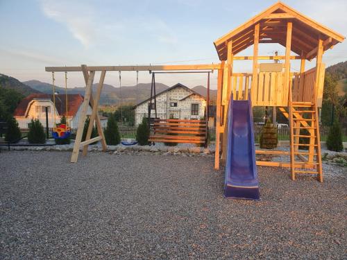 a playground with a slide and a wooden swing set at VILA DAVELY in Câmpulung Moldovenesc