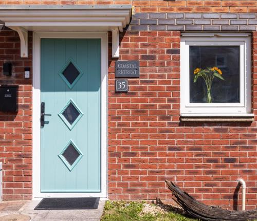 a house with a blue door and a vase of flowers at Coastal Retreat in Carmarthenshire in Llanelli