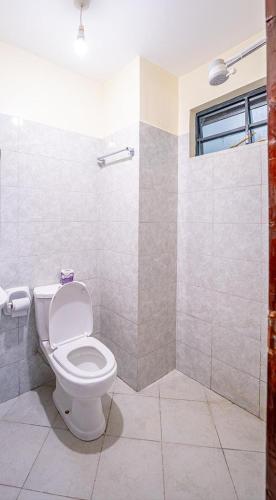 a bathroom with a toilet and a shower at Lux Suites Cavendish Square Apartments in Syokimau