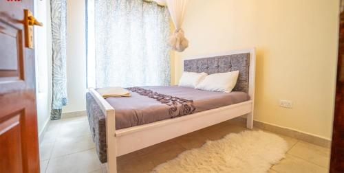 Cama pequeña en habitación con ventana en Lux Suites Cavendish Square Apartments, en Syokimau