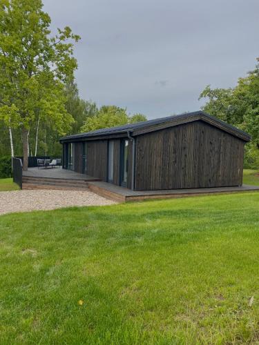 a wooden building with a grass field in front of it at Island House atostogų namai in Gaylyunay