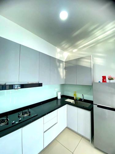 a kitchen with white cabinets and a black counter top at JOVIAL Modern Cozy Suite `Metropol BM BandarPerda in Bukit Mertajam