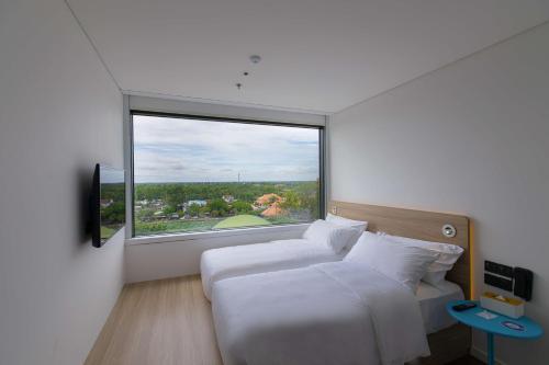 a bedroom with two beds and a large window at SOJO HOTEL CAN THO in Can Tho