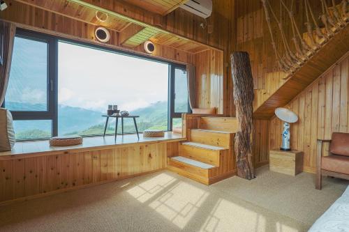 a room with a large window and stairs in a house at Longji One Art Hotel in Longsheng
